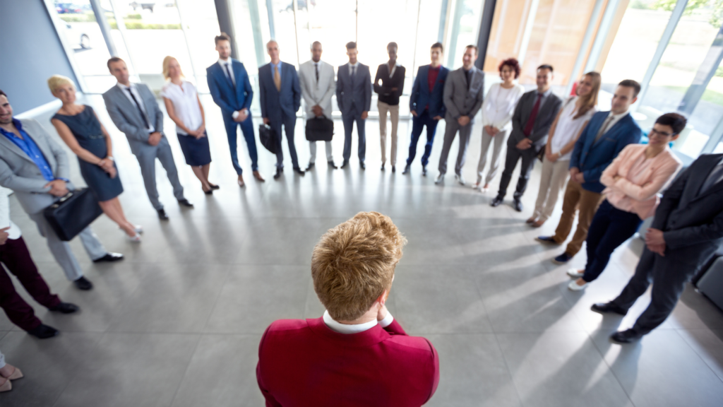 A professional in business attire stands looking into a large reflection of people who may be leading as a finance leader
